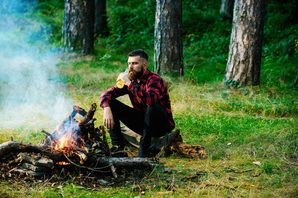 Şenlik ateşinin yanında oturan yakışıklı maço.,