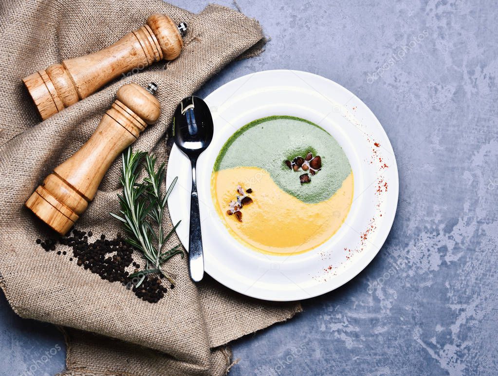 Spinach and pumpkin cream soup on grey texture background