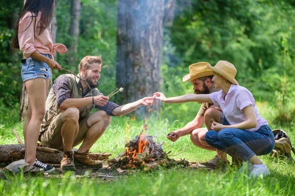 Camping činnosti. Společnost mládež camping Les pražení marshmallows. Pražení marshmallows populární skupiny aktivity kolem ohně. Společnost přátel připravit pečené marshmallows svačinu přírodní pozadí — Stock fotografie