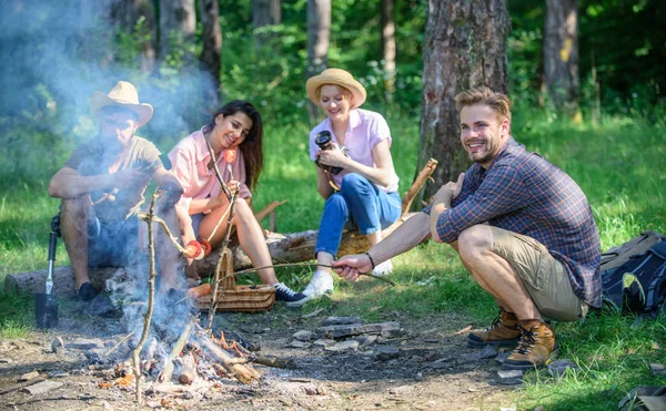 Hikers sharing impression of walk and eating. Summer hike. Picnic with friends in forest near bonfire. Company having hike picnic nature background. Tourists with camera relaxing checking photos