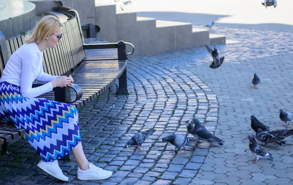 Kvinna turist eller medborgare kasta smulor för duvor. Grupp duvor på city square väntar fester. Flicka utfodring dove fåglar urban bakgrund. Tjej blond kvinna avkopplande torg och mata duvor — Stockfoto