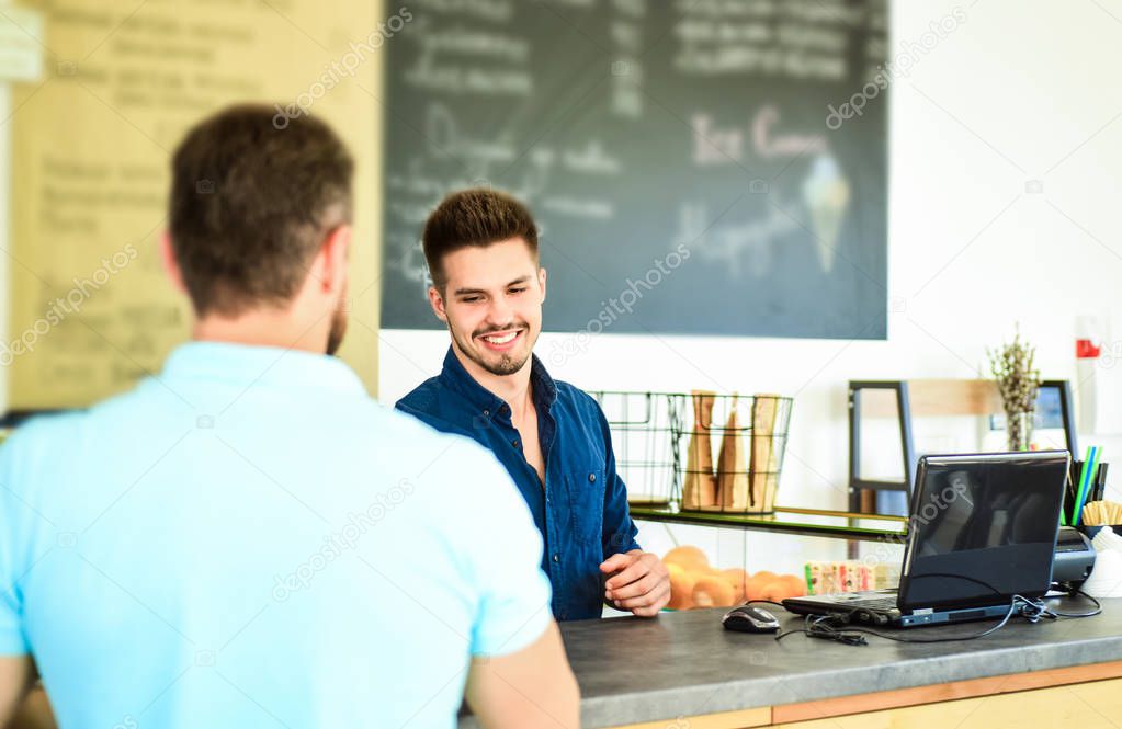 Barista handsome stylish hipster communicate with client visitor. Service staff qualification. Man ask for coffee at bar counter. Barista at bar of modern cafe ready to serve coffee for client