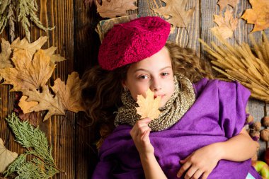Küçük çocuk kız parlak yumuşak örme şapka bere moda. Sonbahar moda aksesuar kavramı. Moda trend sonbahar sezonu. Kız yatıyordu ahşap arka plan yaprakları yukarıdan düşmüş. Aksesuar moda ayrıntı örme