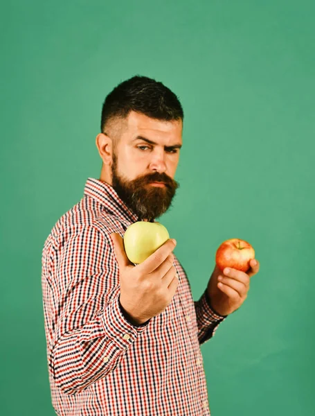 Man with beard holds red and green apples