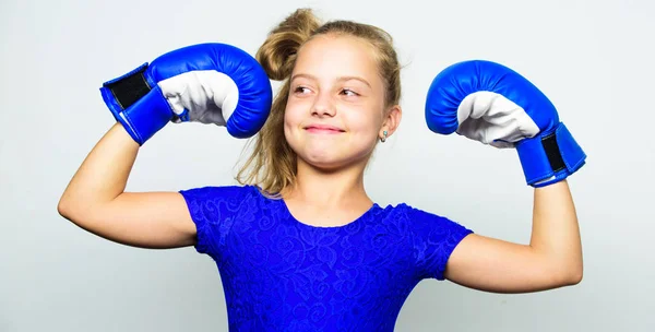 Kid stark och frisk. Flicka barn starkt med boxhandskar poserar på grå bakgrund. Hon känns stark och självständig tjej. Sport uppfostran för flickor. Feministiska rörelsen. Starka barn koncept — Stockfoto