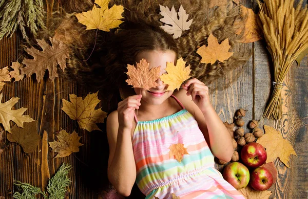 Ребёнок с длинными волосами и опавшими кленовыми листьями. Осень даров природы. Осенний уют рядом. Советы для превращения осенью в лучший сезон. Девочка улыбаясь лицо лежал деревянный фон осенью атрибуты — стоковое фото
