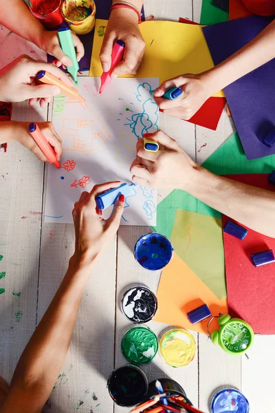 Kunstenaars houten tafel met verf en gekleurd papier — Stockfoto