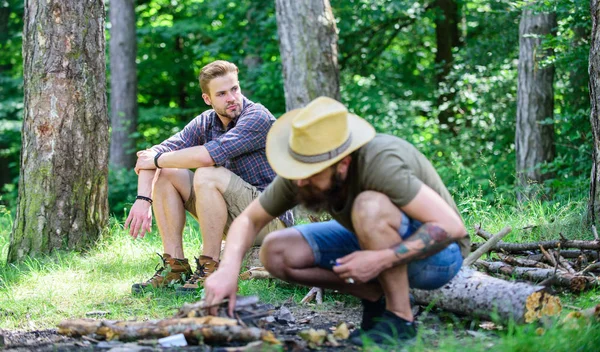 A Camping erdőben. Hogyan építsünk kint a máglya. A férfiak a nyaralás. Ember brutális szakállas csípő előkészíti a máglya erdőben. Gondoskodik az erdőben gallyak, vagy fa botokat. Végső útmutató a máglya — Stock Fotó