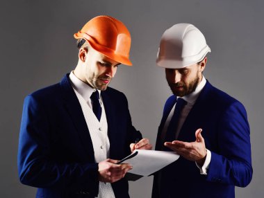 Mimarlar ciddi yüzü olan projeyi tartışmak. Girişimci ve mimar planları bina ile. İnşaat, Mimarlık, ortaklık, iş, iş, tasarım konsepti. Müteahhitler planı binasında bak