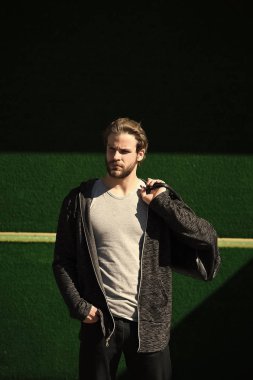 Yeşil arka planda spor çantalı bir adam.