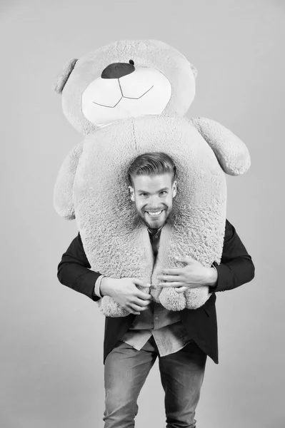 Homem carrega urso de pelúcia gigante no pescoço, fundo cinza. Conceito de presente de aniversário. Teddy urso brinquedo de pelúcia agradável surpresa. Cara de barba feliz cara segura brinquedo ursinho de pelúcia. homem formal terno bonito presente surpresa — Fotografia de Stock