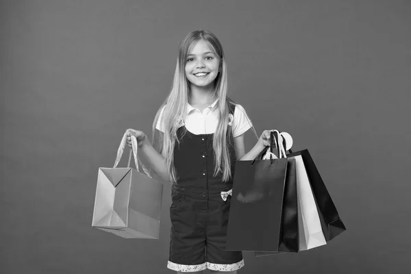 Chica en la cara sonriente lleva racimos de bolsas de la compra, aislado sobre fondo blanco. A la chica le gusta comprar ropa de moda en el centro comercial. Niña con el pelo largo aficionado a las compras. Concepto de compras —  Fotos de Stock