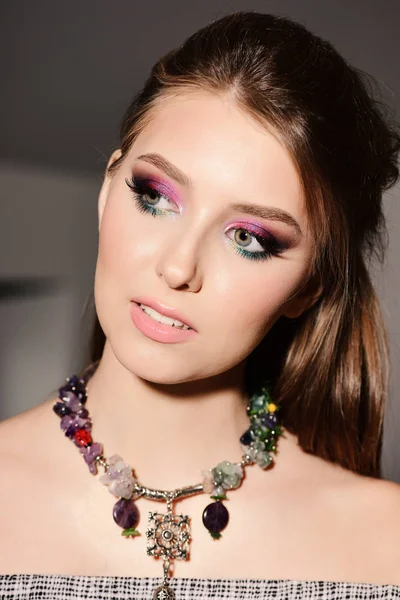 Dziewczyna nosi kolorowy makijaż i naszyjnik z ciekawym wyglądem — Zdjęcie stockowe