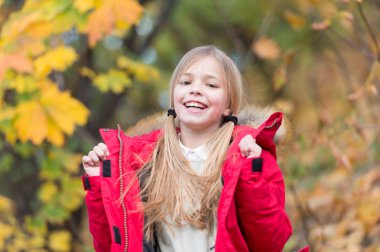 Hayat enerji dolu. Çocuk kız giyim ceket sonbahar sezonu doğa arka plan için. Çocuk sonbahar yürüyüşüne neşeli. Sıcak palto sonbahar için en iyi seçim. Vücut sıcak giysiler sonbahar gün tutun. Sonbahar kıyafeti kavramı