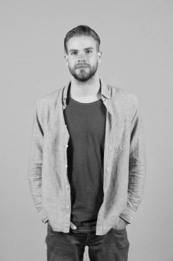 Katı sakallı adam günlük kıyafetler giyer, gri arka plan. Tıraşsız sakallı adam yakışıklı ve bakımlı görünüyor. Sakallı, çekici ve saç stili olan adam. Erkeklik kavramı