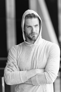 Sakin ve kendinden emin. Tıraşsız kukuletalı kollar yakışıklı ve havalı görünüyor. Sakallı çekici adam görünüşü önemser. Adam ciddi bir yüz, şehir geçmişi, dağılmış. Metroseksüel kavram