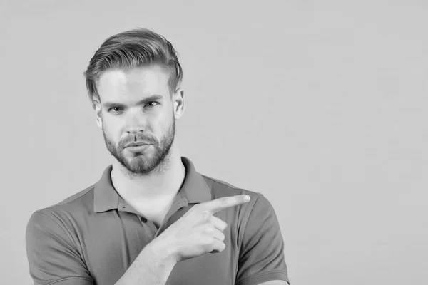 Concepto de publicidad de consejos. Tipo barbudo atractivo señalando el dedo índice a un lado. Hombre cara estricta se ve con confianza, fondo gris. Hombre con barba sin afeitar chico se ve guapo bien arreglado — Foto de Stock