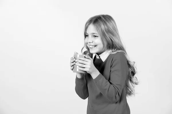 Soif, concept de déshydratation. Sourire d'enfant avec tasse bleue sur fond orange. Fille aux longs cheveux blonds en pull rouge tenir tasse. Santé et boissons saines. Pause thé ou café, espace de copie — Photo