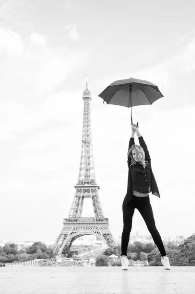 Леди с зонтиком позирует перед Эйфелевой башней, на фоне неба. Дама-туристка спортивная и активная прогуливается по центру Парижа с рюкзаком. Девушка турист любит ходить и осмотреть достопримечательности. Концепция путешествия — стоковое фото