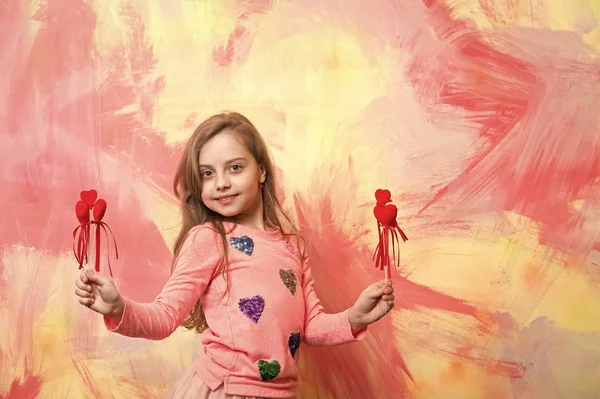 Pequena menina feliz segurando dia dos namorados corações vermelhos decorativos — Fotografia de Stock