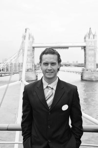 Happy businessman in London, United Kingdom. Man smile at Tower bridge. Tourist enjoy sightseeing in city. Travelling for business and pleasure. Architecture and design concept