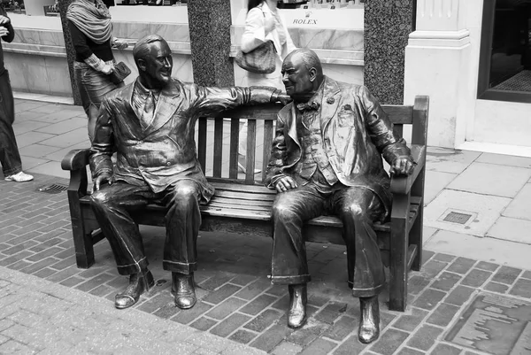 Londres, Reino Unido - 25 de febrero de 2010: la escultura de los hombres se sienta en el banco de bronce. Escultura aliada en la calle. Amigos en la banca muestra relación. Viaje y viaje. Famosa atracción turística — Foto de Stock