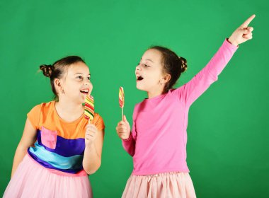 Şekerleme ve çocukluk konsepti. Yuvarlak ve uzun lolipoplu kız kardeşler.
