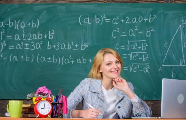 Öğretmen kadın sit tablo kara tahta arka plan. Sınıf organize etmek ve öğrenme süreci kolay ve anlamlı. Öğretmen de düzenli ve kararlı. Mükemmel communicability ve kişilerarası becerileri