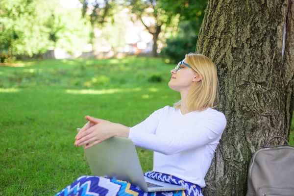 Студент готовит проект. Исследование в женском парке ноутбуков онлайн. Девушка сидит на траве с блокнотом. Девушка пользуется виртуальным образованием. Подумайте минутку, чтобы найти вдохновение. Студенты серфинга в парке — стоковое фото