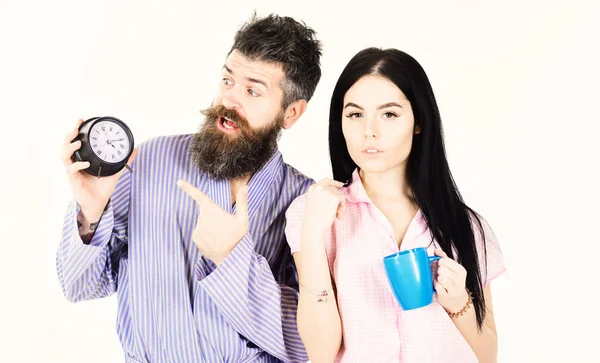 Concepto matutino perfecto. Chica con taza de café, el hombre tiene el reloj en la mano. Pareja, la familia se despertó a tiempo. Pareja enamorada, familia joven en pijama, albornoz aislado sobre fondo blanco —  Fotos de Stock