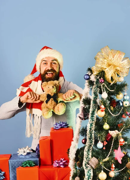 Парень в красной шляпе с подарочными коробками на Рождество и медведь — стоковое фото