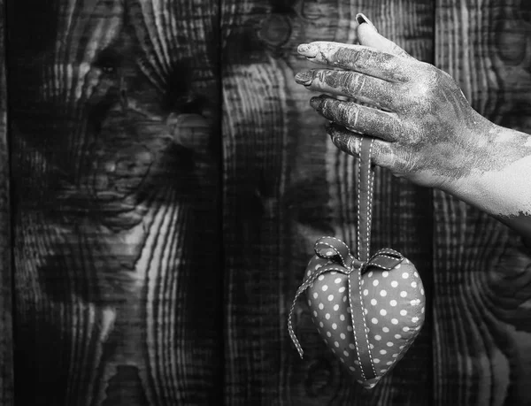 Mano femenina untada en pintura dorada o glister sosteniendo lunares rosados hechos a mano enfoque selectivo corazón de San Valentín sobre fondo de estudio vintage marrón, espacio de copia. —  Fotos de Stock