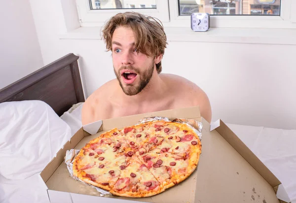 Man bearded handsome guy eating cheesy food for breakfast in bed. Food delivery service. Man likes pizza for breakfast. Who cares about diet. Guy holds pizza box sit bed in bedroom or hotel room — Stock Photo, Image