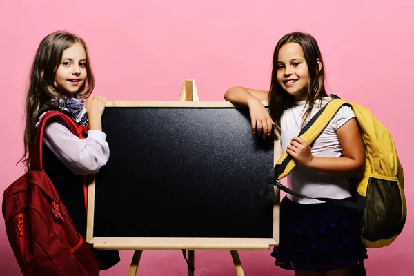 Schulmädchen neben Kreidetafel auf rosa Hintergrund — Stockfoto