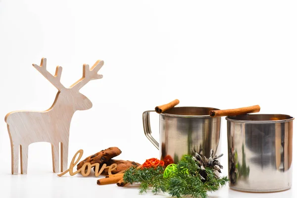 Mulled şarap veya tarçın ile metal mug içinde ev yapımı içki. Sıcak içecekler kavramı. Mulled şarap veya kış dekorasyonu köknar dalı, koni ve beyaz arka plan üzerinde geyik yakınındaki sıcak içecek kupa, yakın çekim — Stok fotoğraf