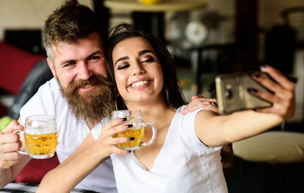 Couple in love on date drinks beer. Best friends or lovers drinking beer in pub. Take selfie photo to remember great date in pub. Man bearded hipster and girl with beer glass full of craft beer