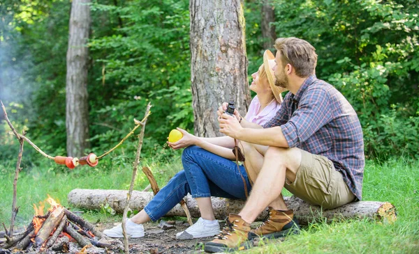 Couple relaxing sit on log having snacks. Hike picnic date. Family enjoy romantic weekend in nature. Pleasant picnic or romantic date nature background. Couple romantic date near bonfire in forest — Stock Photo, Image