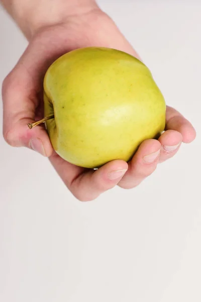 Мужская рука держит светло-зелёное яблоко. Концепция здоровья и питания . — стоковое фото