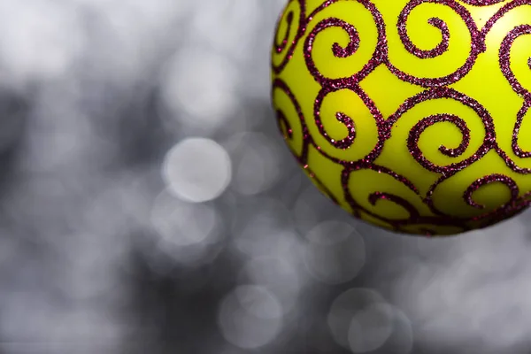 Festlig dekoration för julgran, gul boll med glitter dekor på grå suddig bakgrund, närbild. Prydnad koncept. Juldekoration eller leksak för julgran med skimrande Detaljer — Stockfoto
