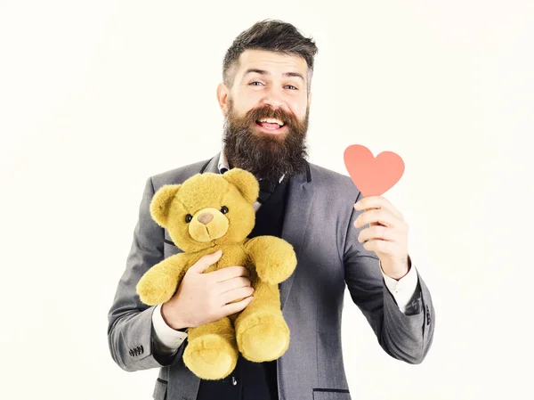 Щасливий зрілий чоловік посміхається, тримаючи плюшевого ведмедя з серцем — стокове фото