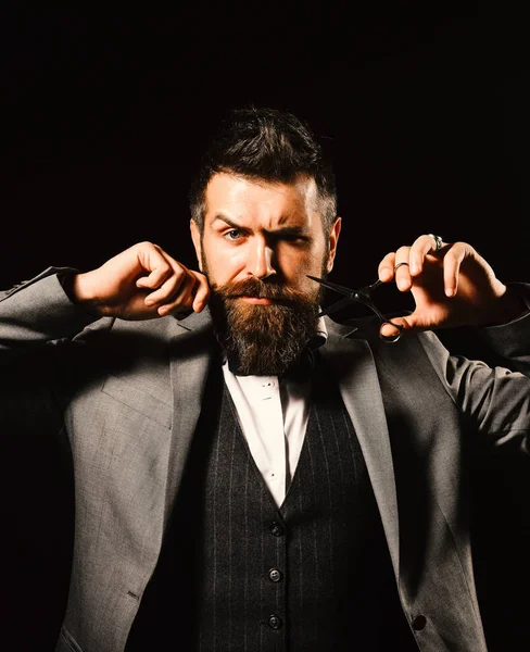 Maço takım elbiseli, bıyıklı ve sakallı.