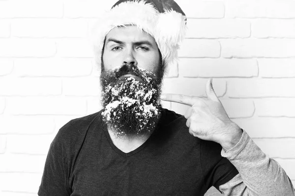 Bell'uomo barbuto con baffi alla moda e lunga barba innevata su gravi spettacoli viso su di esso su sfondo muro di mattoni bianchi . — Foto Stock