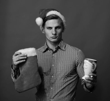 Noel Baba kırmızı arka planda çorap ve fincan aksesuarları tutuyor..