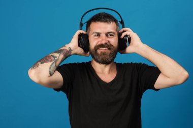 Adamın kulaklığı mavi arka planda. Sakallı DJ.