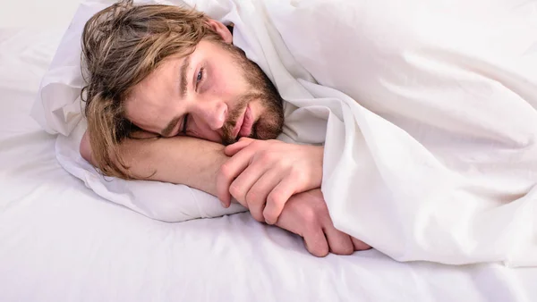 Homem sem barba cama relaxante bonito. Homem sonolento sonolento sem barba rosto coberto com cobertor tendo descanso. O tipo deitou-se debaixo de roupas brancas. Conceito de roupa de cama fresca. Deixe seu corpo se sentir confortável — Fotografia de Stock