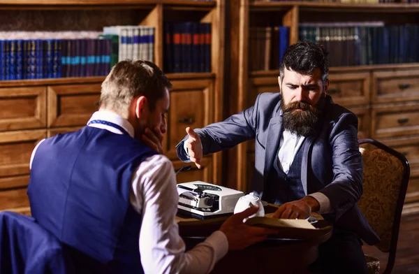 Man with beard interviews writer. Man in suit or journalist