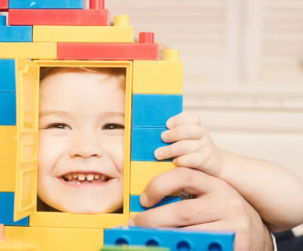 Niño mirando a través de la puerta de la casa de juguete hecha de bloques . — Foto de Stock