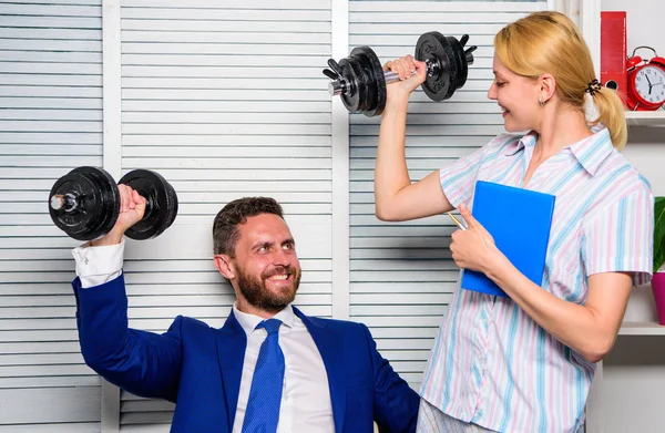 Healthy habits in office. Man and woman raise heavy dumbbells. Strong powerful business strategy. Good job concept. Boss businessman and office manager raise hand with dumbbells. Strong business team