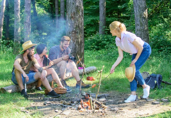 Summer picnic. Tourists hikers sit on log relaxing waiting picnic snack. Picnic with friends in forest near bonfire. Hikers relaxing during snack time. Company having hike picnic nature background.