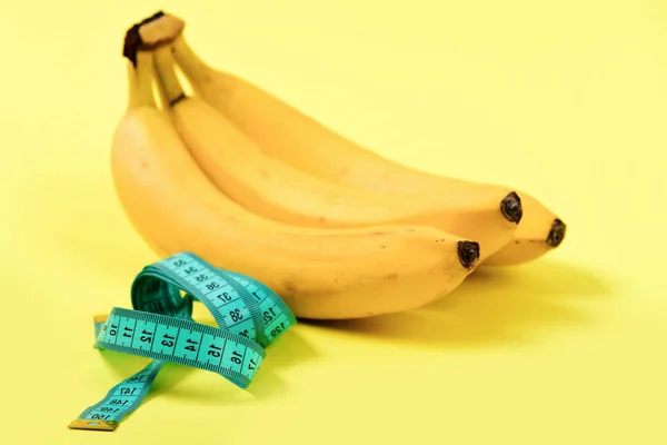 Cinta para medir en color turquesa junto a racimo de plátanos — Foto de Stock